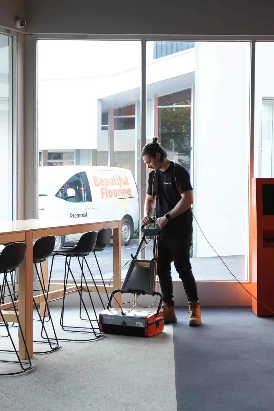 A Premrest technician with a floor machine beside the Premrest van